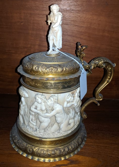 A 19th century German ormolu mounted ivory tankard, carved in relief with a frieze of tritons and nude bathers